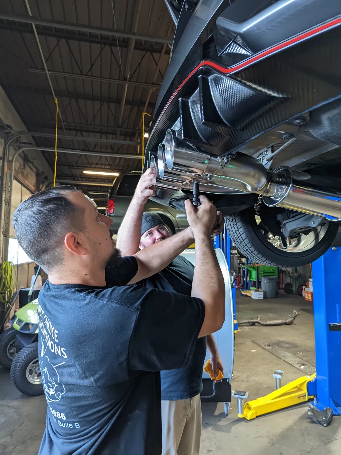 Jeff and Tim fitting a performance exhaust beneath a vehicle at The Engine Block